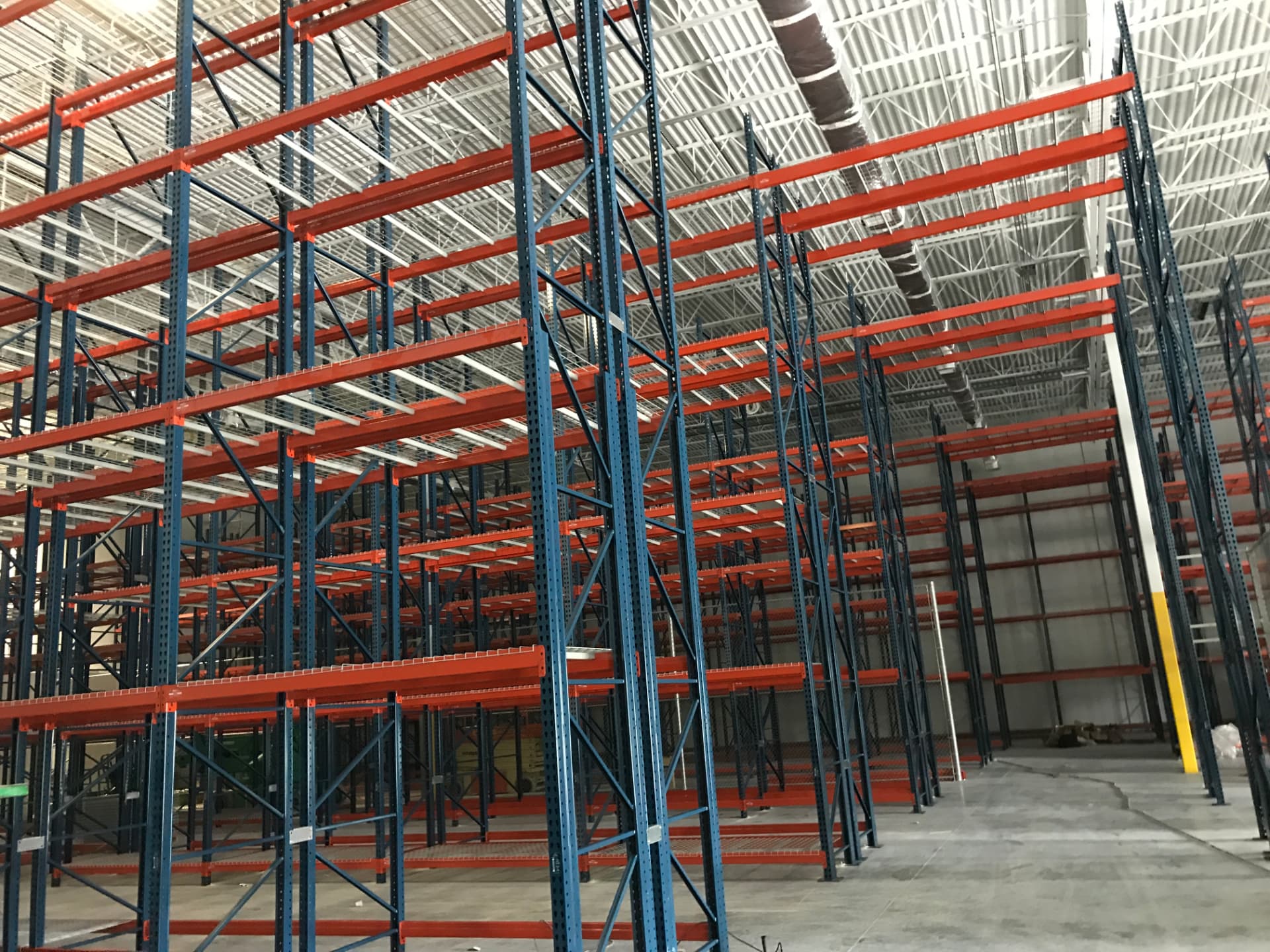 High-density warehouse pallet racking with tall blue uprights and orange crossbeams